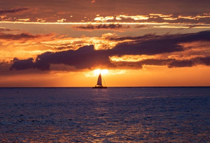 Lone sailboat on West Maui water during sunset
